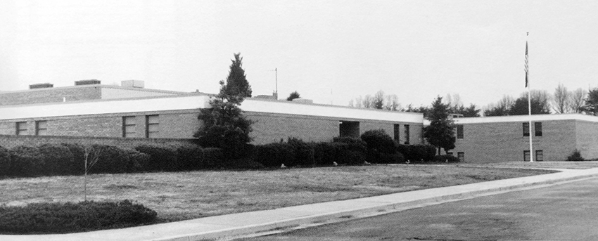 Black and white photograph of the front exterior of Fort Hunt Elementary School from our 1988 to 1989 yearbook. The building is pictured in its original configuration before any additions had been constructed.  